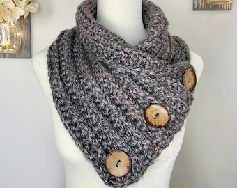 May include: A gray and pink infinity scarf with three wooden buttons. The scarf is on a white mannequin.