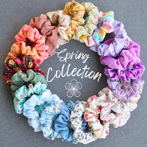 Peut inclure: Une collection de chouchous en tissu colorés dans une variété de motifs, y compris des fleurs, du tie-dye et des couleurs unies. Les chouchous sont disposés en cercle et le texte "Spring Collection" est écrit au centre. Le texte "@tamarascreativesoul" est écrit en bas de l'image.