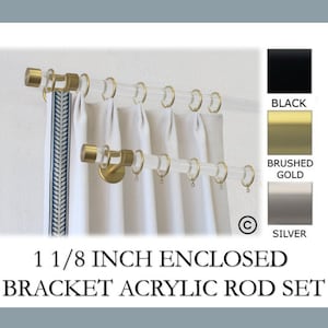 May include: Clear acrylic curtain rod set with brushed gold accents. The set includes rings and brackets. The image also shows color swatches for black, brushed gold, and silver. The text reads: 1 1/8 inch enclosed bracket acrylic rod set.