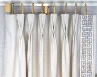 May include: White curtains with a geometric pattern border hanging from a gold curtain rod.