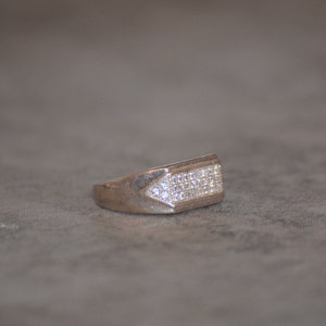 May include: A silver ring with a rectangular top set with small clear stones.