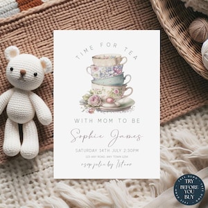 Puede incluir: Una tarjeta de invitación blanca con el texto "TIME FOR TEA" y "WITH MOM TO BE". Presenta una pila de tazas de té florales y el nombre "Sophie James". Un oso de peluche de ganchillo está a la izquierda. La invitación es para un baby shower.