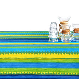 Könnte beinhalten: Drei Glas-Kaffeemaschinen mit Holzgriffen auf einer blau-grün-gelb gestreiften Tischdecke.