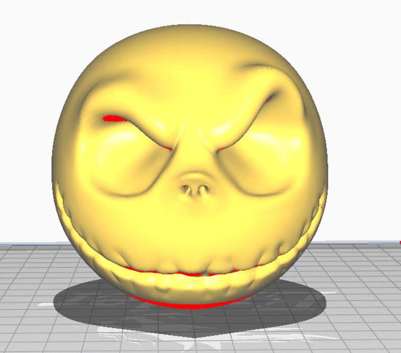 May include: A yellow 3D printed model of Jack Skellington's face from the movie The Nightmare Before Christmas. The model has a wide grin with sharp teeth and red eyes.