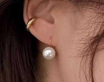 May include: A pair of gold earrings with a single pearl dangling from one earring.