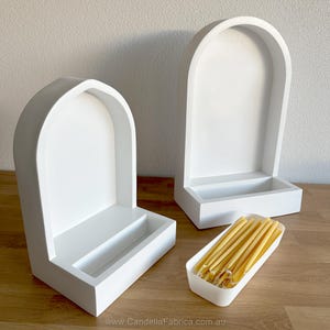 May include: Two white, arched-top wooden display shelves with a rectangular base. A small white tray holds several yellow candles. The shelves are on a wooden surface. The website address "www.CandellaFabrica.com.au" is visible at the bottom.
