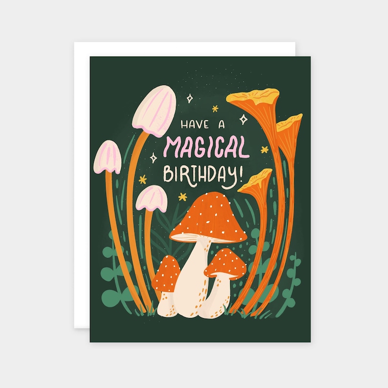 Greeting card with words "Have a magical birthday!" with trippy orange, beige, pink mushrooms (shiitake, enoki, toadstool, chanterelles) around with foliage and stars on a dark forest green background