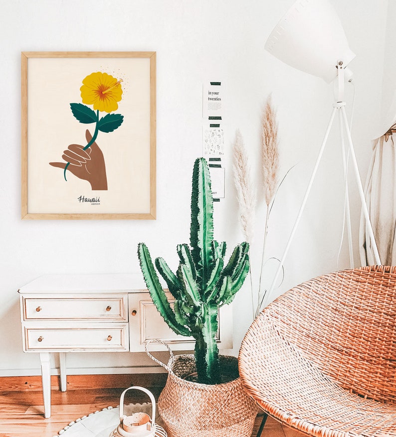 May include: A framed print with a yellow hibiscus flower and a hand making the Hawaiian sign language for "Aloha". The print has the word "Hawaii" written below the image.