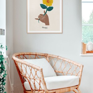 May include: A framed print with a yellow hibiscus flower and a brown hand making the shaka sign. The text "Hawaii" is below the flower.