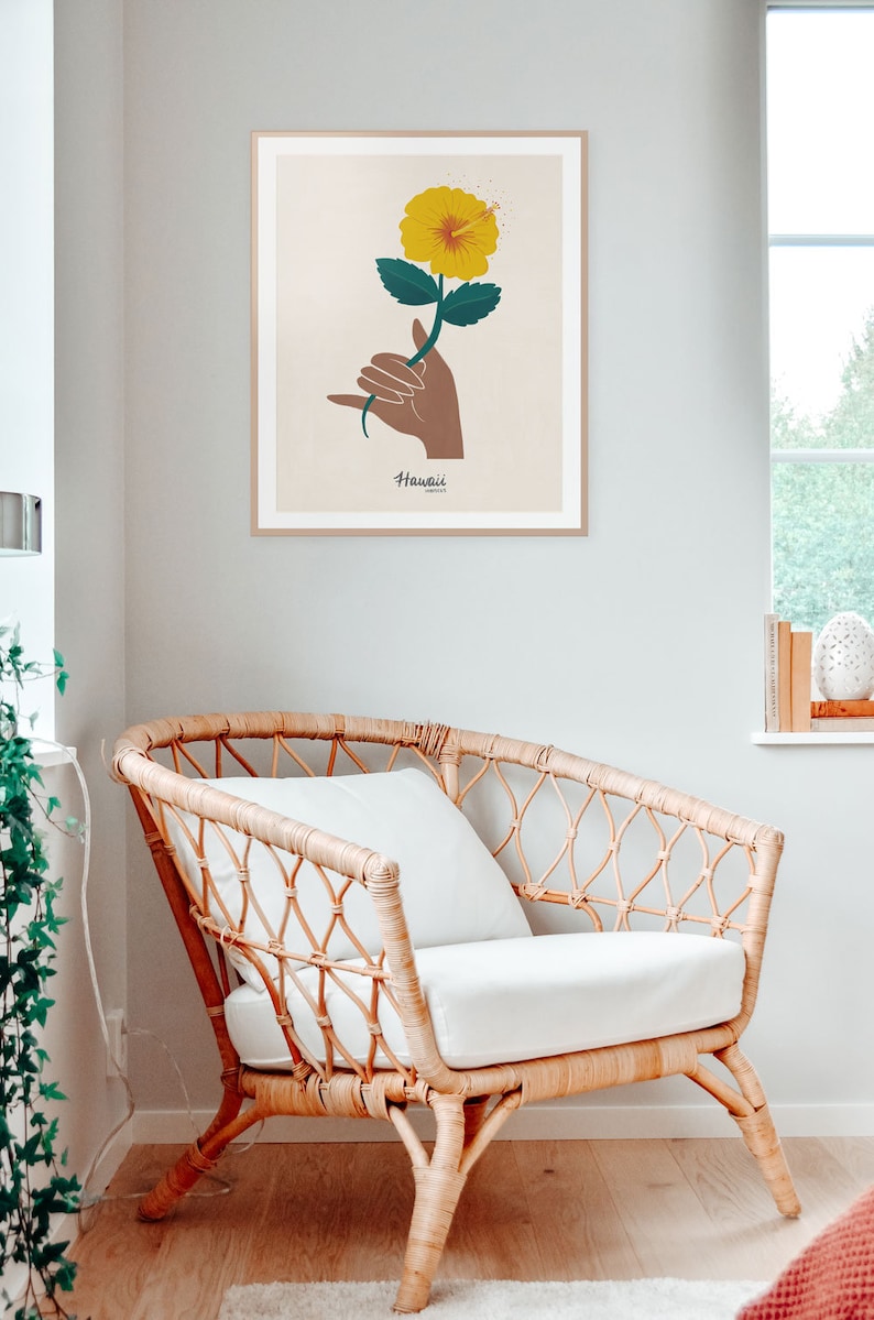 May include: A framed print with a yellow hibiscus flower and a brown hand making the shaka sign. The text "Hawaii" is below the flower.