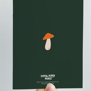 Greeting card with words "Have a magical birthday!" with trippy orange, beige, pink mushrooms (shiitake, enoki, toadstool, chanterelles) around with foliage and stars on a dark forest green background