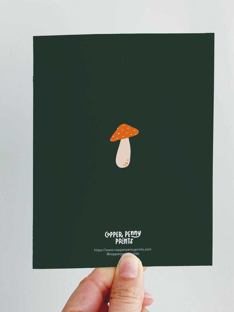 Greeting card with words "Have a magical birthday!" with trippy orange, beige, pink mushrooms (shiitake, enoki, toadstool, chanterelles) around with foliage and stars on a dark forest green background