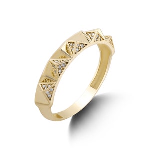 May include: A gold ring with a geometric design featuring small diamonds set into the band.