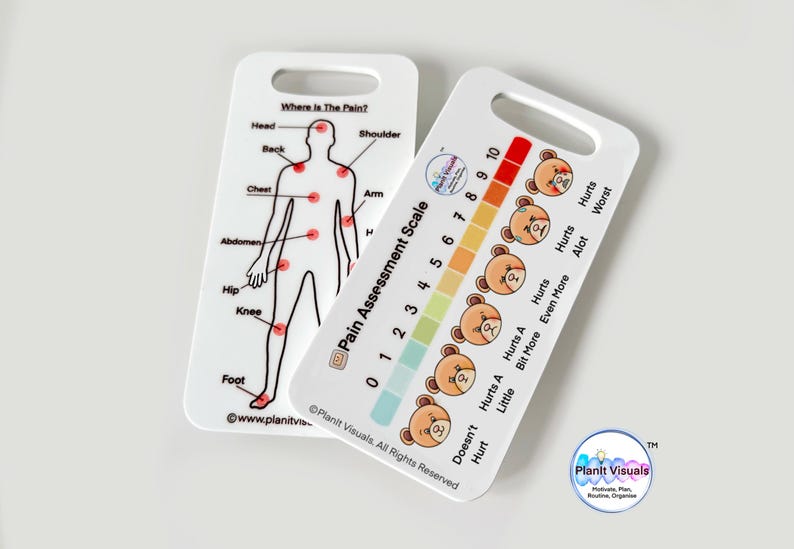 May include: Two white plastic cards with a pain assessment scale. The first card shows a stick figure with red dots on different body parts. The second card has a pain scale with numbers 0-10 and bears with different facial expressions. The text on the cards reads "Where is the Pain?" and "Pain Assessment Scale".