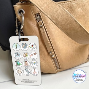 May include: A white card with colorful icons and text. The card has a ring attached to the top and is hanging from a tan leather purse. The card says "Walk, Choose, More, Quiet Space, Food, Help, Learn, Too Bright, Bath,  Rise, Chore, Thank You". The card also says "Name: Lisa Smith" and "Plant Visuals".