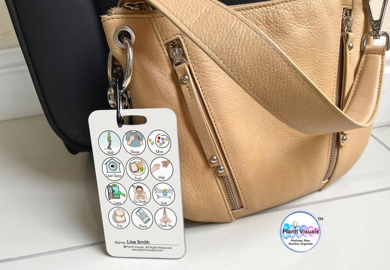 May include: A white card with colorful icons and text. The card has a ring attached to the top and is hanging from a tan leather purse. The card says "Walk, Choose, More, Quiet Space, Food, Help, Learn, Too Bright, Bath,  Rise, Chore, Thank You". The card also says "Name: Lisa Smith" and "Plant Visuals".