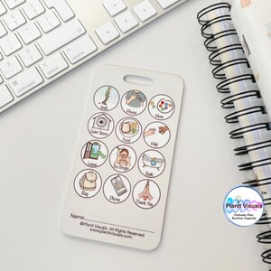 May include: White communication board with 16 round icons featuring various images and text. The icons include images of a tree, a person, a hand, food, a bath tub, a backpack, a phone, and hands in a praying position. The text includes words like "walk", "more", "food", "help", "bath", "bag", "phone", and "thank you". The board also includes the text "Planit Visuals" and "www.planitvisuals.com".