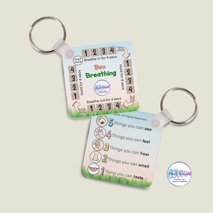 May include: Two square keyrings. One has instructions for box breathing, with the text "Box Breathing" and numbered steps. The other lists "5 Things you can see" and other sensory prompts. The keyrings have metal rings.