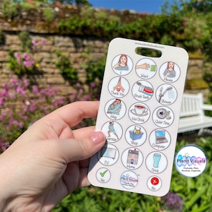 May include: A white communication card with colorful illustrations and text. The card has a hole at the top and includes images and words for common phrases like "I want", "Thank you", "Please", "Hug", "Hot Drink", "Quiet Time", "Shop", "Computer", "TV", "Home", "Drink", "Yes", and "No".