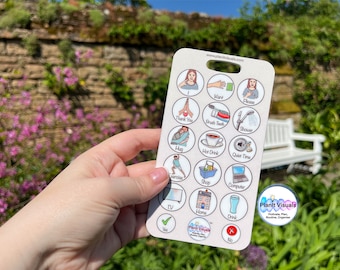 May include: A white communication card with colorful illustrations and text. The card has a hole at the top and includes images and words for common phrases like "I want", "Thank you", "Please", "Hug", "Hot Drink", "Quiet Time", "Shop", "Computer", "TV", "Home", "Drink", "Yes", and "No".