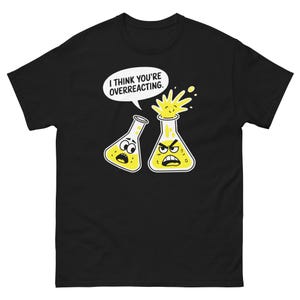 Puede incluir: Camiseta negra con una burbuja de diálogo blanca que dice "Creo que estás reaccionando exageradamente". Se muestran dos vasos de precipitados de dibujos animados, uno con una expresión tranquila y el otro con una expresión enojada y una explosión amarilla que sale de él.