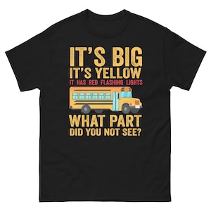 Puede incluir: Camiseta negra con una ilustración de autobús escolar amarillo y el texto "IT'S BIG IT'S YELLOW IT HAS RED FLASHING LIGHTS WHAT PART DID YOU NOT SEE?"