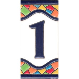 Op de afbeelding: Een witte keramische tegel met het blauwe cijfer "1" in het midden. De tegel is versierd met een kleurrijke mozaïekrand van rood, oranje, geel, groen en blauw.
