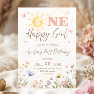 May include: A watercolor-style invitation for a first birthday. The design features a smiling sun, butterflies, and floral accents. Text includes "Happy Girl" and details for Amelia's first birthday celebration.