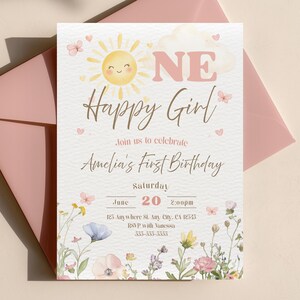 May include: A light-colored invitation card with the text "ONE Happy Girl" and "Amelia's First Birthday". The card features a smiling sun, butterflies, and floral illustrations. A pink envelope is in the background.