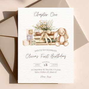 May include: A watercolor-style invitation for a first birthday celebration. The design features a stack of books, a stuffed bunny, floral accents, and wooden blocks spelling "ABC". The text reads "Chapter One" and "Olivia's First Birthday".