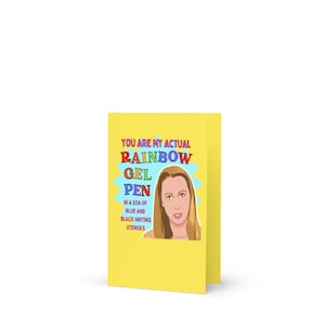 May include: A yellow card with the text "You are my actual rainbow gel pen in a sea of blue and black writing utensils". A cartoon illustration of a woman with blonde hair is in the centre of the card.