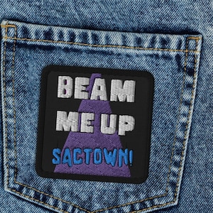 May include: A black and purple embroidered patch with the text "Beam Me Up Sactown!" on a blue denim background.