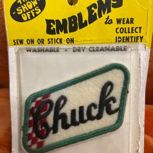 May include: Embroidered "Chuck" patch with a white background, green border, and red and white checkered detail. The patch is packaged with a yellow backing that reads "The Show-Offs" and "Emblems to Wear, Collect, Identify."