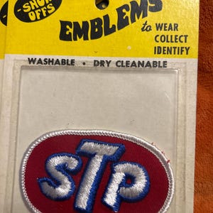 May include: Embroidered STP patch on a yellow backing card. The patch is oval, with a red background and white and blue lettering. The card reads "The Show Offs" and "Emblems to Wear, Collect, Identify."