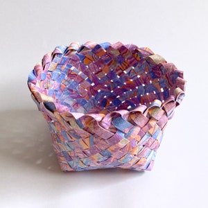 May include: A woven basket made from paper with a purple, blue, and orange pattern.