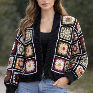 May include: A long-sleeve cardigan constructed from individual crochet granny squares in shades of red, yellow, green, and white, framed by black yarn borders. The garment features a solid black ribbed knit collar, cuffs, and hemline.