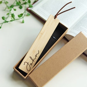 May include: A personalized wooden bookmark with the name "John" engraved on it. The bookmark is in a brown cardboard box with a black velvet lining.