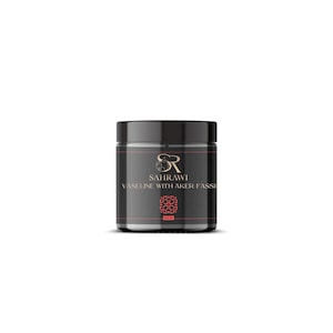 May include: A black jar with a black lid. The jar has a label with the text "SAHRAWI" and "VASELINE WITH AKER FASSI" in white and a logo in gold and red. The jar is sitting on a white background.