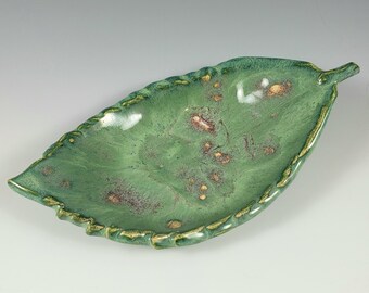 May include: A green ceramic leaf-shaped dish with a textured edge and gold flecks throughout.