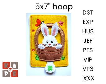 May include: A 5x7 inch embroidery hoop with a felt design of a white bunny in a brown basket with green grass. The bunny has pink ears and a pink nose. There is a yellow butterfly and a pink flower on the felt. The hoop is yellow with a red border.