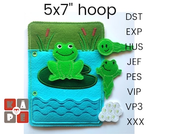 May include: A felt quiet book with a green frog sitting on a lily pad, a green tadpole, and a white egg with green spots. The book is 5x7 inches and has a blue water background with green grass and reeds.