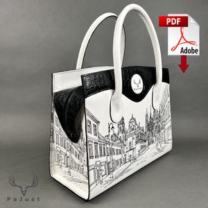 Puede incluir: Bolso de mano blanco y negro con un diseño de paisaje urbano. El bolso tiene asas y una parte superior negras, con una detallada ilustración en blanco y negro de una escena callejera. El bolso tiene un logotipo que dice "PaJust".