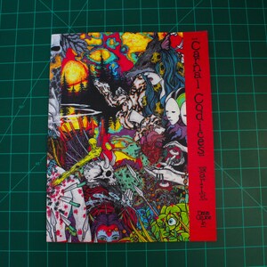 May include: A colorful book cover with a red spine and the title "Carnal Codices" in black text. The cover features a surreal, graphic design with a wolf, a skull, and other imagery.