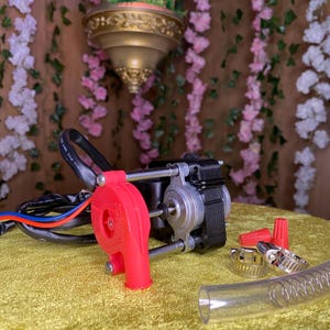 May include: A red and black electric blower with a clear plastic hose, two wire connectors, and two hose clamps. The blower is on a gold fabric surface.