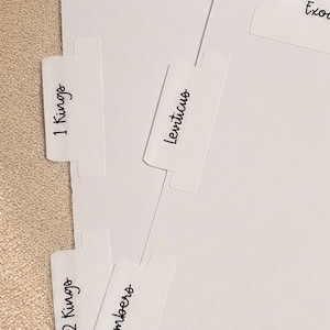 May include: A set of white paper index tabs for a Bible, each featuring black printed text including 2 Samuel, 1 Kings, 2 Kings, Leviticus, Numbers, Deuteronomy, and Exodus. The tabs are arranged in a staggered layout on white paper sheets.