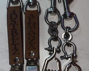 Puede incluir: Cuatro clips de metal con ganchos giratorios. Dos clips cuentan con correas de cuero marrón grabadas con el texto 4DSTREETZ y ALMANZA. Los otros dos clips están unidos a cadenas de metal y mecanismos con resorte de color plateado.