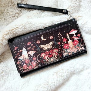 May include: Black leather wallet with a floral print featuring mushrooms, butterflies, crystals, and a crescent moon. The print is on a dark background with white stars.