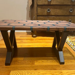 May include: A rectangular coffee table with a wooden top featuring a honeycomb design with teal resin inlays. The table is supported by black metal legs, creating a modern aesthetic. The table measures approximately 48 inches long and 24 inches wide.