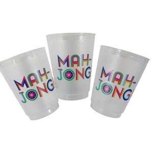 Puede incluir: Tres vasos de plástico translúcidos con la palabra "MAH-JONG" impresa en letras coloridas. Los vasos tienen una forma ligeramente acampanada y son adecuados para bebidas. El diseño incluye un elemento floral.