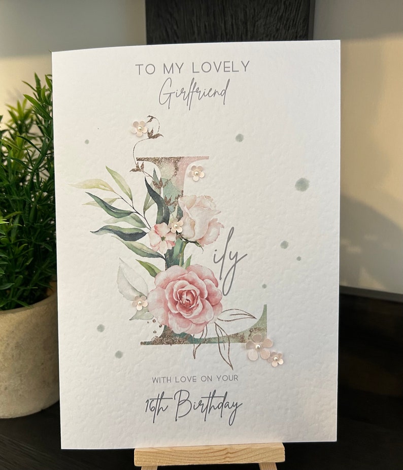 May include: A white card with a floral design and the text "To my lovely Girlfriend with love on your 16th Birthday".